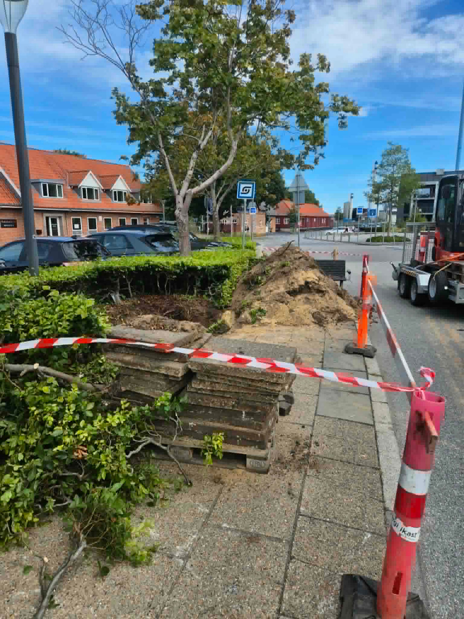 Afspærret gravearbejde med jordbunke og stablede fliser i Ikast bymidte